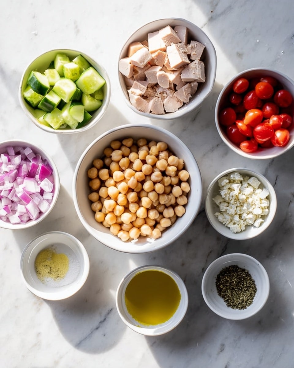 The image shows a top view of several small white bowls arranged on a white marbled surface with ingredients for a salad. In the center, there is a white bowl filled with light brown chickpeas. Surrounding it are smaller bowls: one with light green cucumber pieces, one with cubed light pink chicken, one with crumbled white feta cheese, one with chopped red onions, and one with chopped red tomatoes. Additionally, there are three small white bowls with liquid and dry seasonings—one has a golden yellow oil, another has a clear light liquid, and the last has coarse salt and herbs. Soft shadows fall across the scene, giving it a natural daylight feel. Photo taken with an iphone --ar 4:5 --v 7