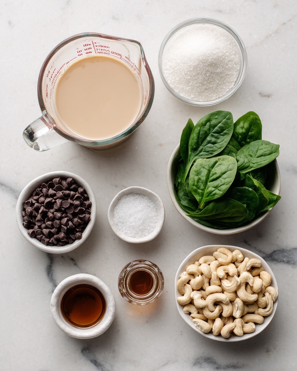 The image shows eight small containers of ingredients placed on a white marbled surface. At the top left, there is a clear glass measuring cup filled with a creamy beige liquid labeled soymilk. To its right, a small white bowl holds white granulated sugar. Below the sugar, a small white shallow dish contains coarse white salt. On the middle right, a white bowl is filled with fresh green spinach leaves. Below the spinach, another white bowl is filled with light beige raw cashew nuts. On the bottom left, a small white bowl holds dark vegan mini chocolate chips. Next to it, there is a small glass bottle with brown vanilla extract, and near the bottle is a tiny clear container with peppermint extract. Each item is clearly labeled with black text, and the scene is bright and clean, set against the smooth white marbled texture. photo taken with an iphone --ar 4:5 --v 7