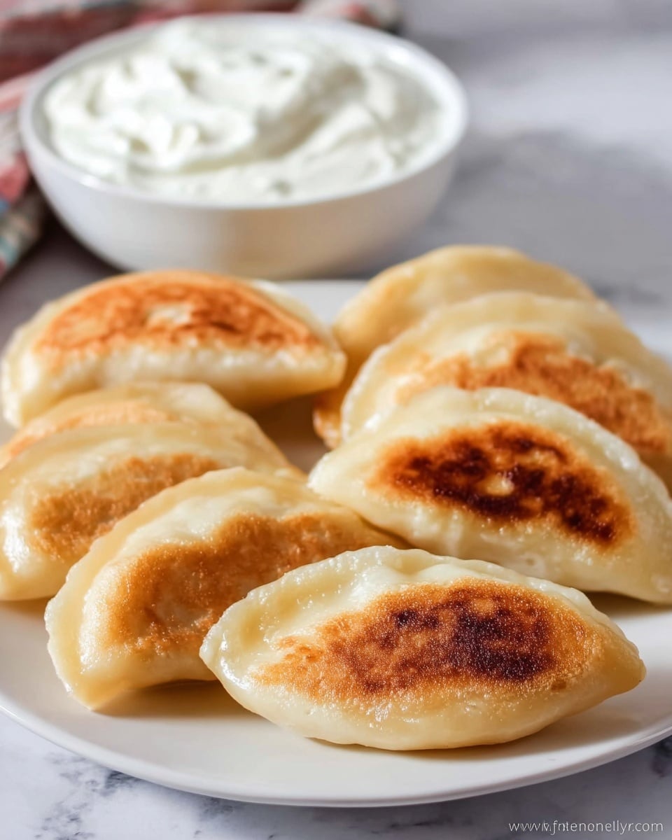 On a white plate, there are five dumplings with a golden-brown fried side facing up, showing a soft and slightly shiny dough on the other parts. In the center of the dumplings, there is a dollop of white sour cream topped with small bits of cracked black pepper. In the background, there is a white bowl filled with more sour cream sitting on a white marbled surface, and a green and blue striped cloth is partially visible behind the plate. The lighting is soft, giving the food a warm, inviting look photo taken with an iphone --ar 4:5 --v 7