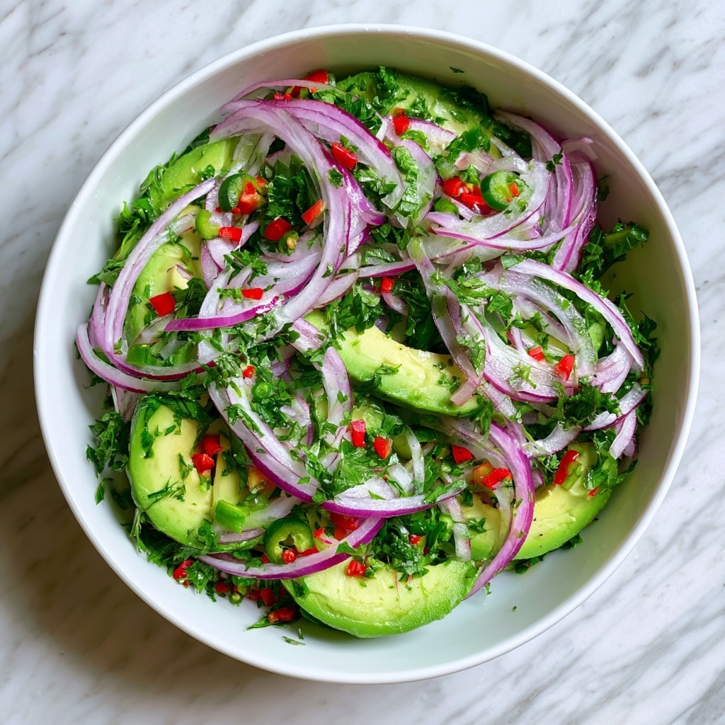 A white bowl filled with a fresh salad is shown on a white marbled texture. The salad has several layers starting with thick slices of green avocado on the bottom and middle. Thin slices of purple-red onion are spread evenly over the avocado, creating a light and airy texture. Small pieces of red and green chili peppers are scattered across the salad, adding small bright spots of red and green color. Fresh green chopped herbs are sprinkled all around, adding a touch of leafy texture and color contrast. The whole salad looks fresh, colorful, and healthy. photo taken with an iphone --ar 4:5 --v 7