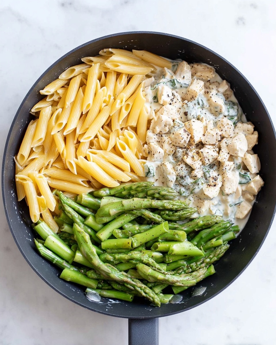 A black frying pan shows three sections of food on a white marbled surface: on the top left, there is a layer of plain yellow penne pasta; on the top right, there is a creamy white sauce with small chunks of light-colored chicken and black pepper sprinkled on top; at the bottom, there are bright green asparagus stalks, cut into smaller pieces with a fresh texture, placed overlapping each other. photo taken with an iphone --ar 4:5 --v 7