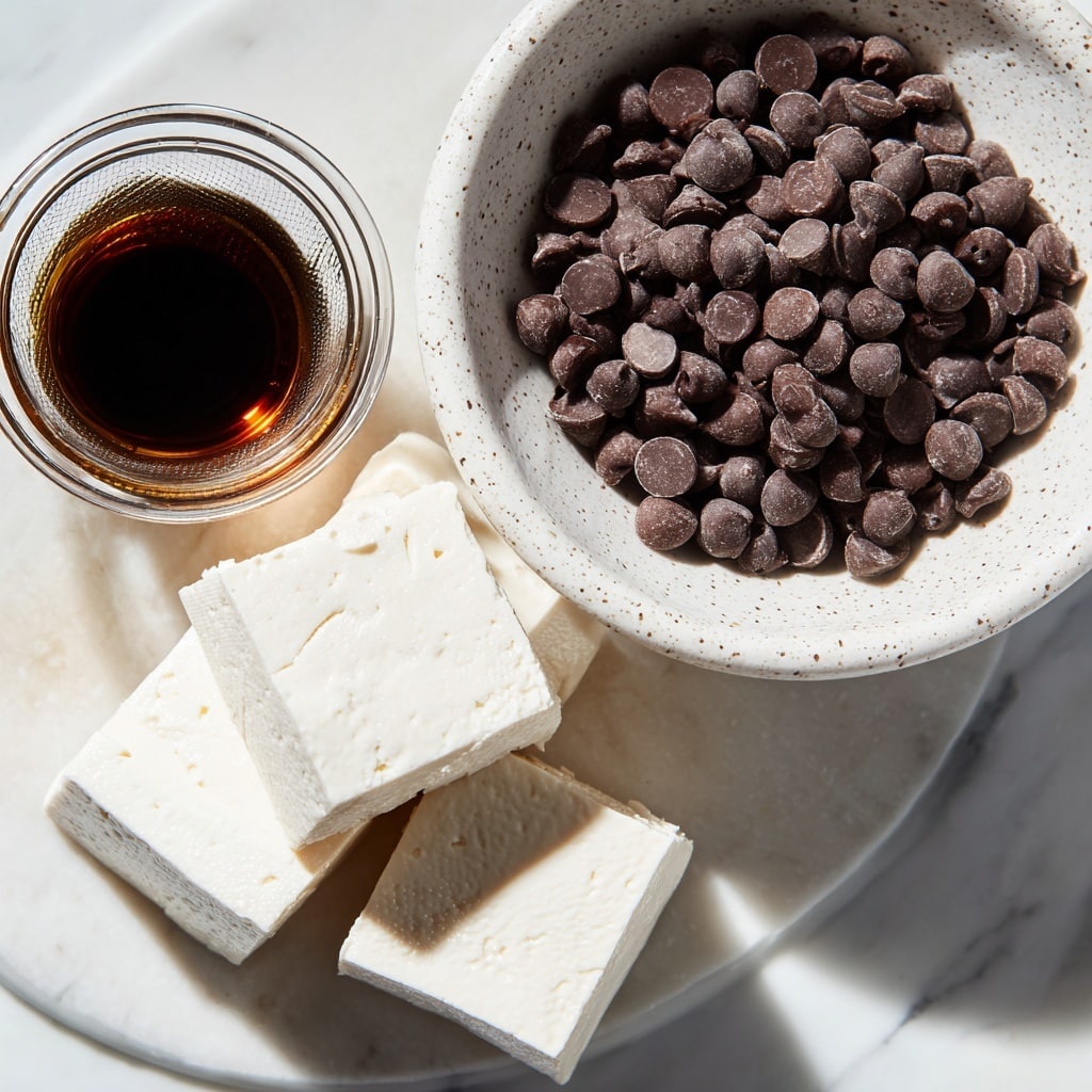 A close-up image shows three ingredients on a white marbled surface: a large white speckled bowl filled with many dark brown vegan semi-sweet chocolate chips in the upper right, a small clear glass jar containing dark brown vanilla extract at the center left, and a white strainer holding three large blocks of smooth, white silken tofu at the bottom right. The light creates a soft shine on the tofu blocks, and the texture of the chocolate chips contrasts with the smooth tofu. Photo taken with an iphone --ar 4:5 --v 7