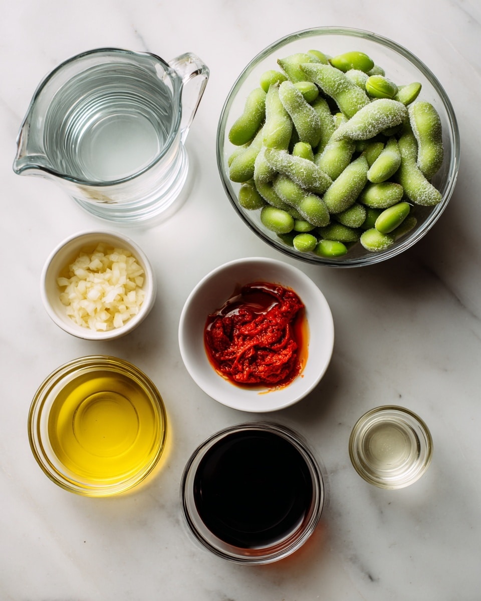 The image shows seven ingredients on a white marbled surface. On the top right, there is a clear glass bowl filled with frozen edamame pods covered with frost. At the top left, there is a clear glass pitcher with water. Below that, a small white bowl holds chopped garlic. Below the garlic, another small white bowl contains bright red chili paste. To the right of the chili paste, a small clear glass jar has dark soy sauce. At the bottom left, a clear glass bowl holds yellow oil. Finally, next to the soy sauce jar, there is a tiny clear glass cup with light-colored rice vinegar. Each ingredient is neatly placed and spaced out, all set against the smooth white marbled surface. photo taken with an iphone --ar 4:5 --v 7
