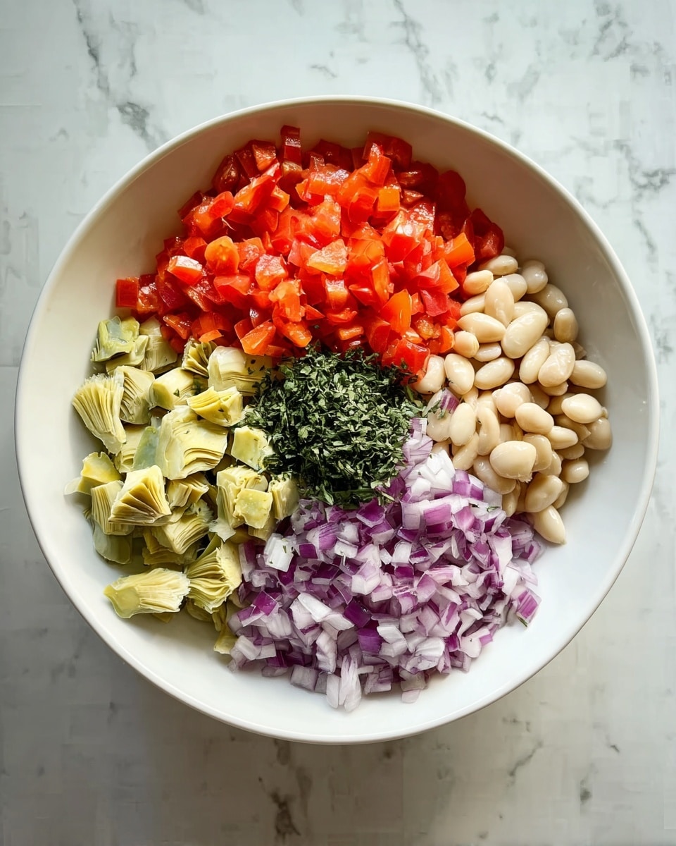A white bowl holds five separate layers of ingredients, each placed side by side without mixing. At the top in bright red-orange are small diced tomato pieces, next to creamy white beans on the right. Below the beans, finely chopped purple onions add a sharp color contrast. To the left of the onions, light pale green artichoke hearts are cut into chunks. At the center of the bowl, a small pile of finely chopped dark green herbs rests, adding freshness and richness. The bowl sits on a white marbled surface. photo taken with an iphone --ar 4:5 --v 7