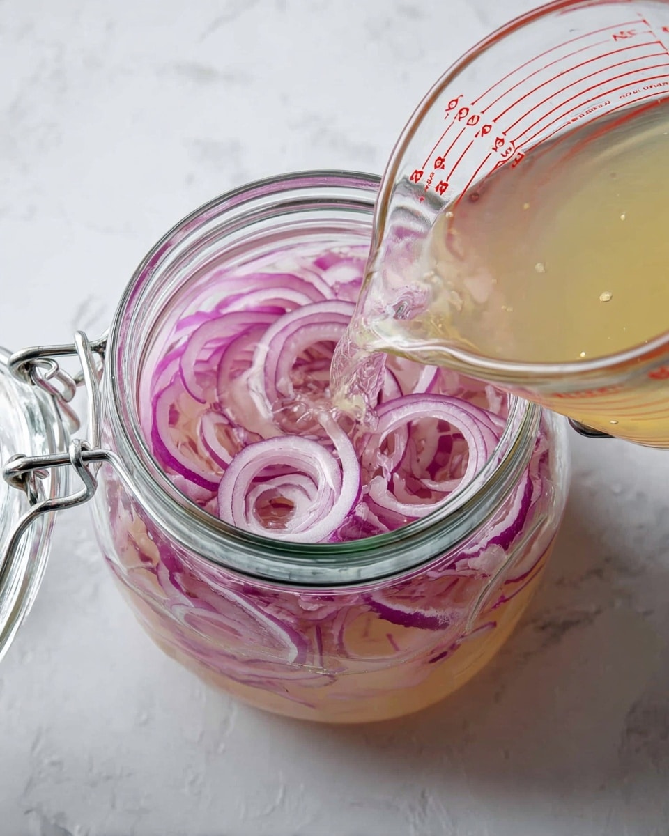 A clear glass jar with a metal clasp is open and filled with thin slices of purple and white onion rings that float in a light pink liquid inside the jar. A transparent measuring cup with red markings is pouring a pale yellow liquid into the jar. The jar and cup sit on a white marbled surface. photo taken with an iphone --ar 4:5 --v 7