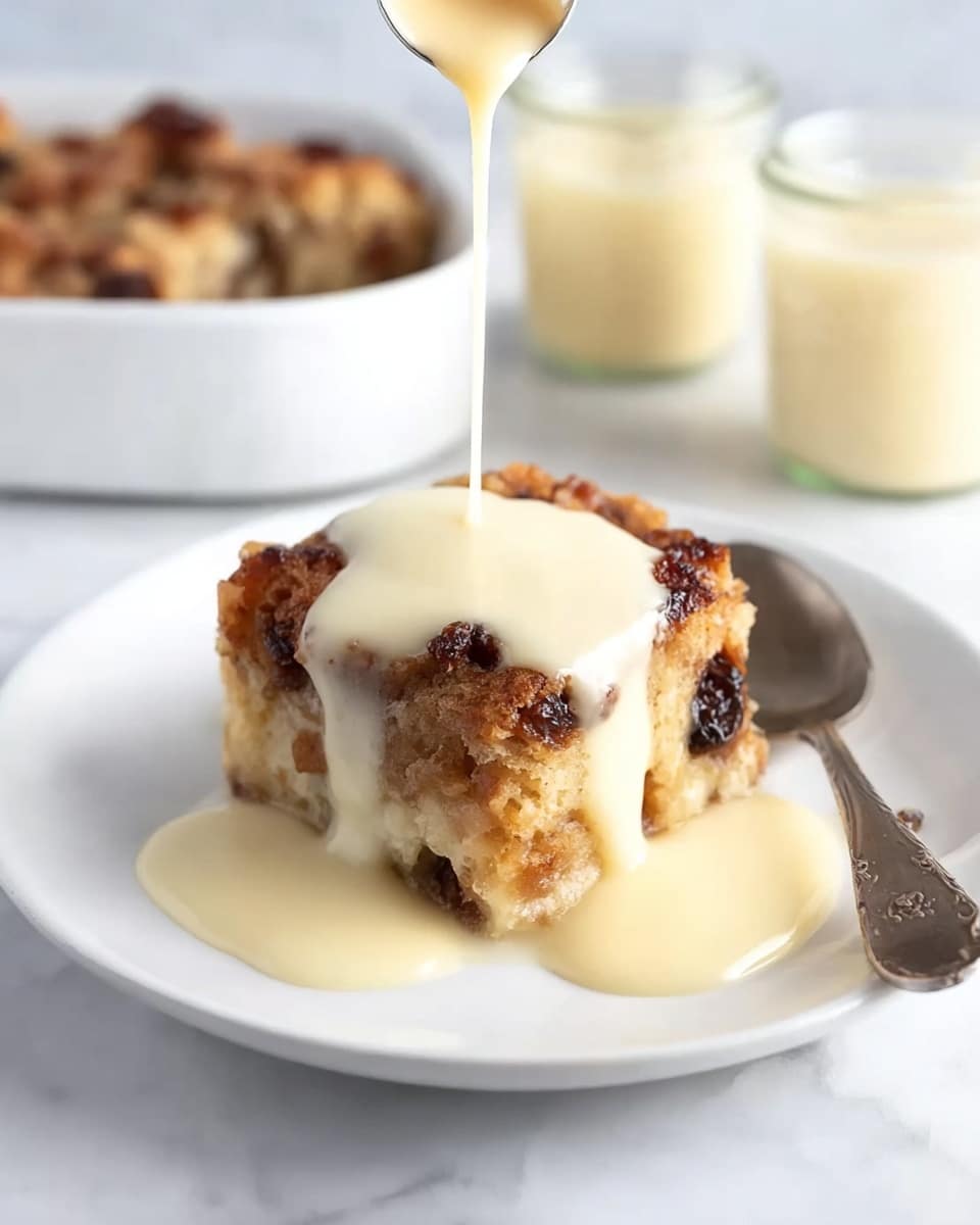 A square piece of bread pudding sits in the center of a white plate on a white marbled surface. The bread pudding has a textured top layer with a golden-brown color and some darker spots from raisins or dried fruit. Creamy pale yellow sauce is poured in thick streams over the top, slightly pooling around the base of the pudding. A silver spoon lies next to the bread pudding on the plate. In the background, there are small glass jars filled with more bread pudding and sauce visible but softly blurred. Photo taken with an iphone --ar 4:5 --v 7