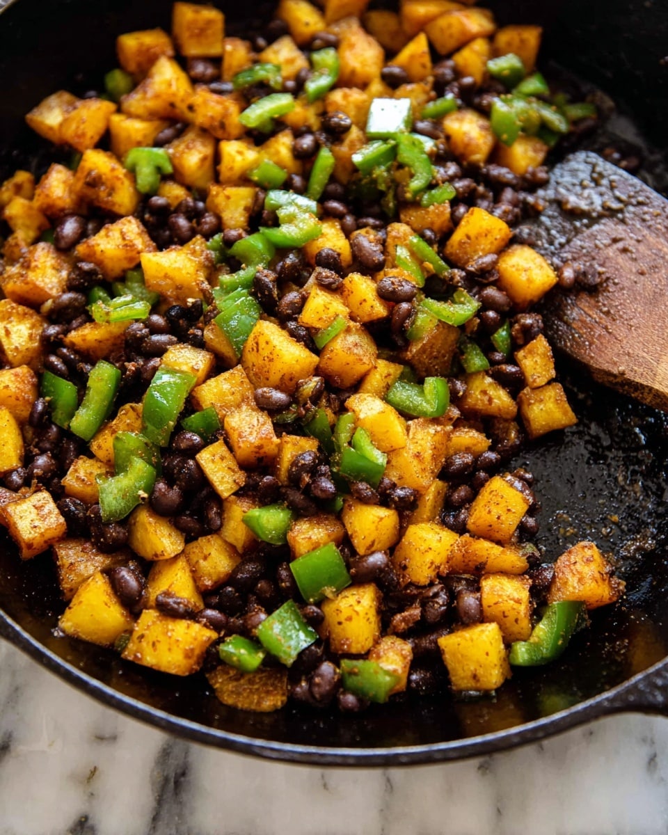 The image shows a close-up of a black cast iron skillet filled with cooked diced yellow potatoes, black beans, and chopped green bell peppers. The potatoes are golden brown with a slightly crispy texture, scattered evenly throughout the skillet. The black beans provide a dark, smooth contrast, mixed closely with the potatoes. The green bell peppers are bright green, cut into medium chunks, adding fresh color and texture. A wooden spatula is partially visible on the right side, resting inside the skillet. The skillet sits on a white marbled surface. photo taken with an iphone --ar 4:5 --v 7