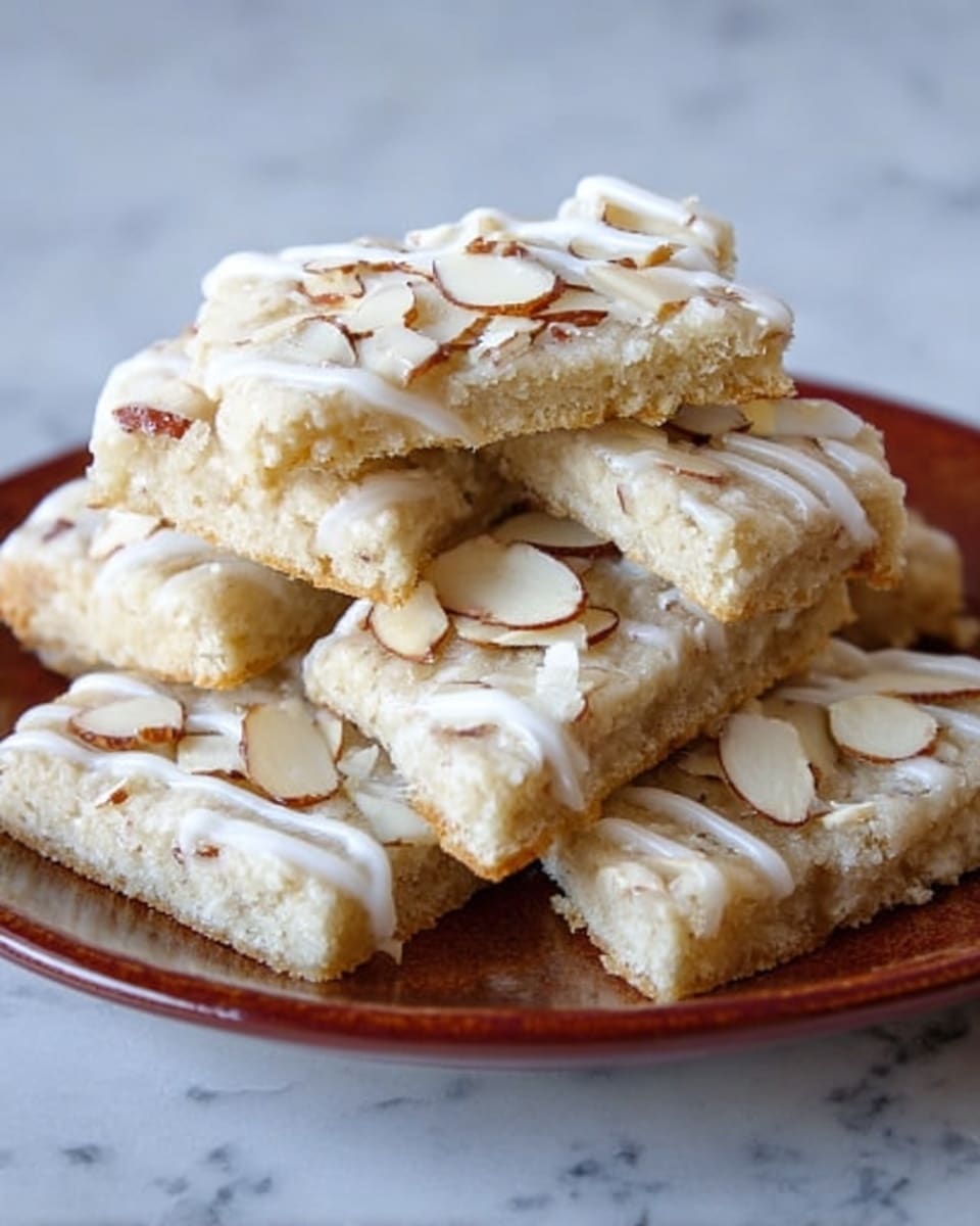 The image shows a stack of seven light beige cookie bars on a white plate, each bar topped with drizzles of white icing and sprinkled with thin sliced almonds. The cookies have a soft, crumbly texture and are arranged overlapping each other in a pile. The background is a white marbled surface that contrasts with the plate and cookies. photo taken with an iphone --ar 4:5 --v 7