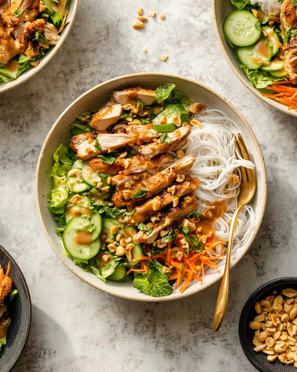 A white bowl holds a layered dish starting with thin white rice noodles on one side. Next to the noodles is a colorful mix of fresh green lettuce, sliced cucumber, and shredded orange carrots, topped with green herbs scattered throughout. On top, golden-brown grilled chicken pieces are arranged in the middle, drizzled with light brown peanut sauce. There are also slices of green jalapeño and crunchy peanuts sprinkled on top. The bowl sits on a white marbled surface with a gold fork inside the bowl, a small black bowl with peanuts to the right, and more bowls with similar dishes partially visible nearby photo taken with an iphone --ar 4:5 --v 7