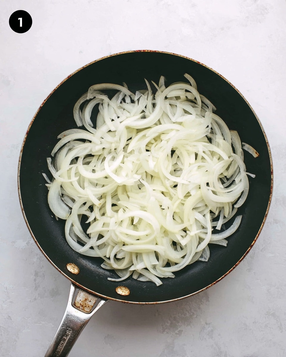 A black frying pan filled with a single layer of thinly sliced white onions spread evenly across the pan's surface, their smooth, slightly translucent texture showing fresh onion layers with some light shine. The pan has a metal handle with small wear marks, and it sits on a white marbled surface that softly reflects light. Photo taken with an iphone --ar 4:5 --v 7