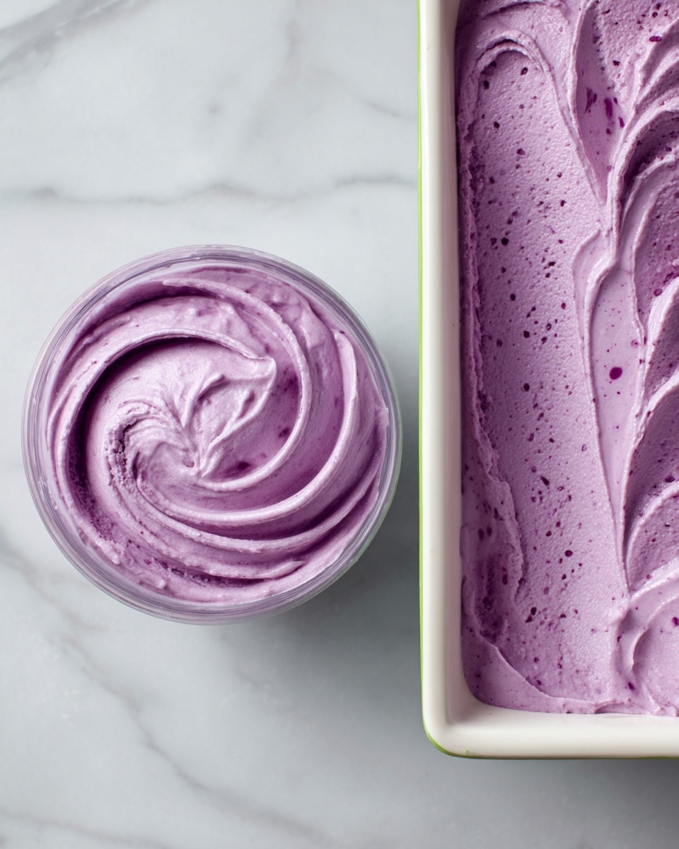 The image shows two views of a thick, smooth purple mixture with a creamy texture. On the left, the mixture is inside a clear bowl, swirled in a circular pattern, with a light, even purple color and some small darker spots. On the right, the same purple mixture is spread evenly inside a white rectangular container with a green rim, ready to be frozen. Both scenes have a clean white marbled surface background. The mixture looks soft and slightly glossy, with no additional layers visible. photo taken with an iphone --ar 4:5 --v 7